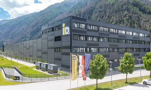 Industriestandort mit modernem Gebäudekomplex in alpiner Umgebung – repräsentiert die innovativen Technologien und Fertigungskompetenz der Pletzer Industrie.